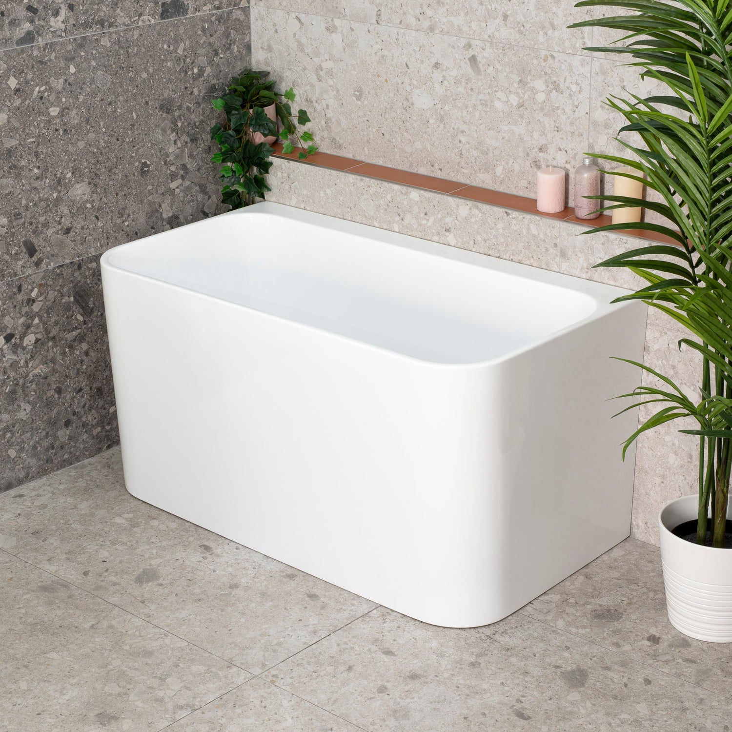 Estus Back to Wall Japanese Soaking Bathtub with Seat in matte white, set against a stone wall in a modern bathroom.